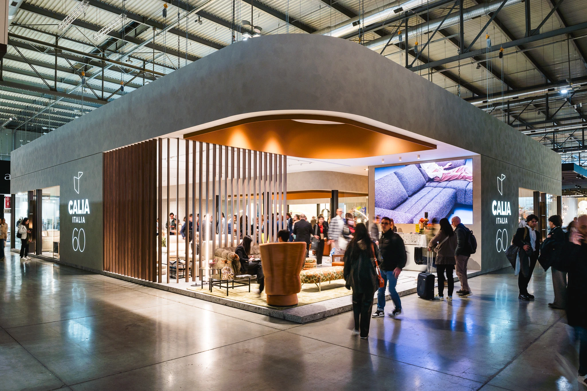 Modern exhibition stand at Salone del Mobile Milano with contemporary furniture and visitors.