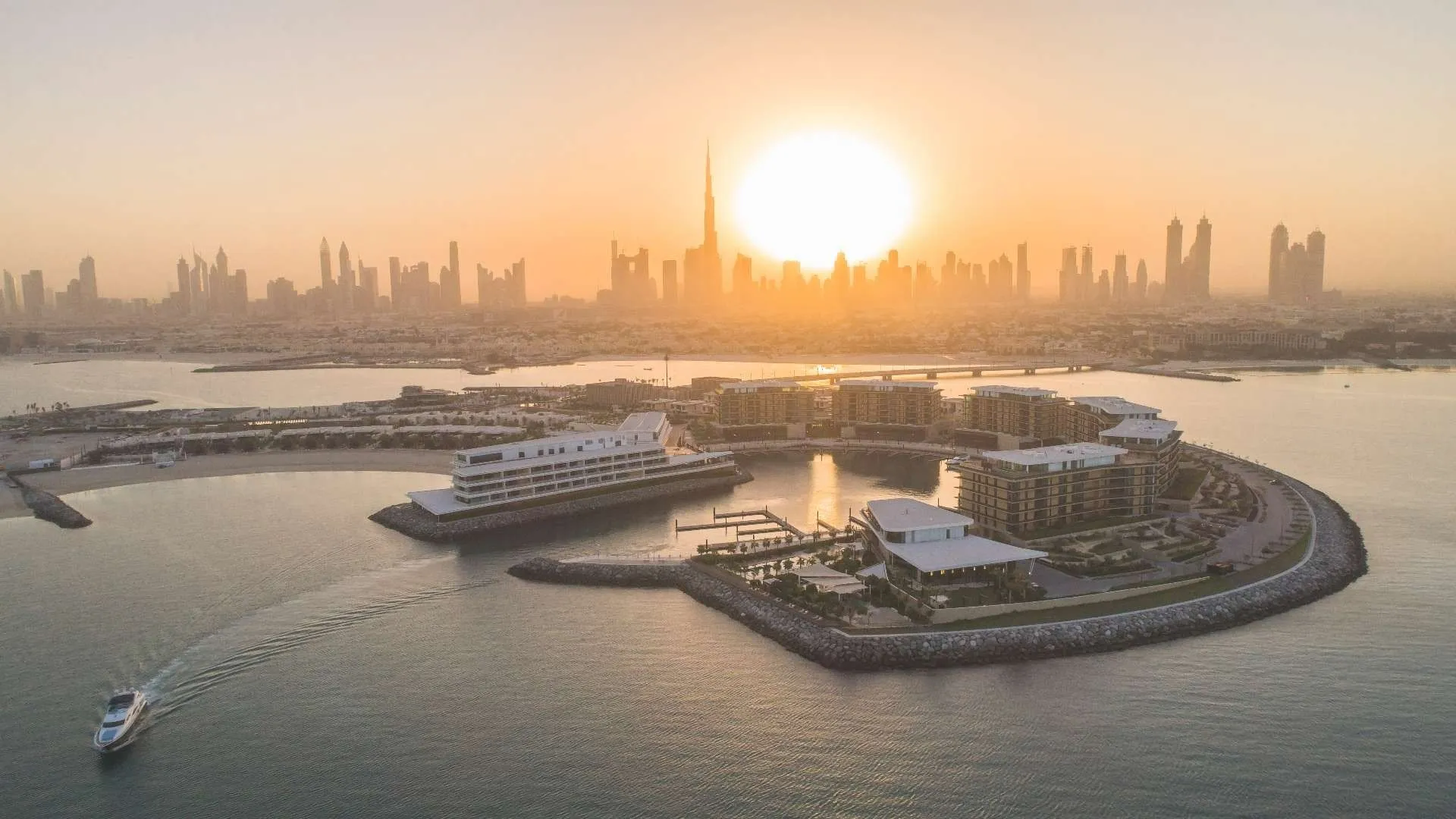 Panoramic aerial view of The Bulgari Resort Dubai with the city skyline at sunset.