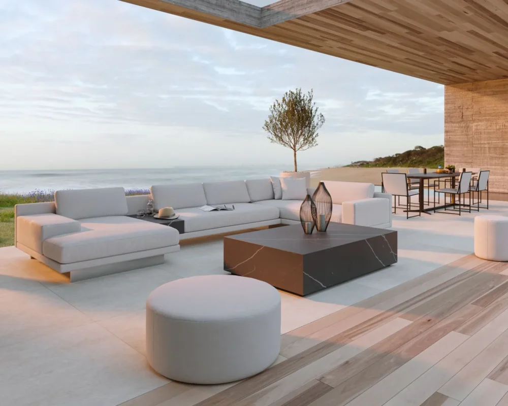Luxury beachfront terrace with white sectional sofa, modern black marble coffee table, and ocean views.