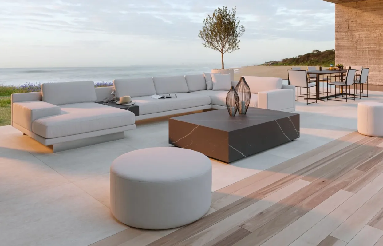 Luxury beachfront terrace with white sectional sofa, modern black marble coffee table, and ocean views.