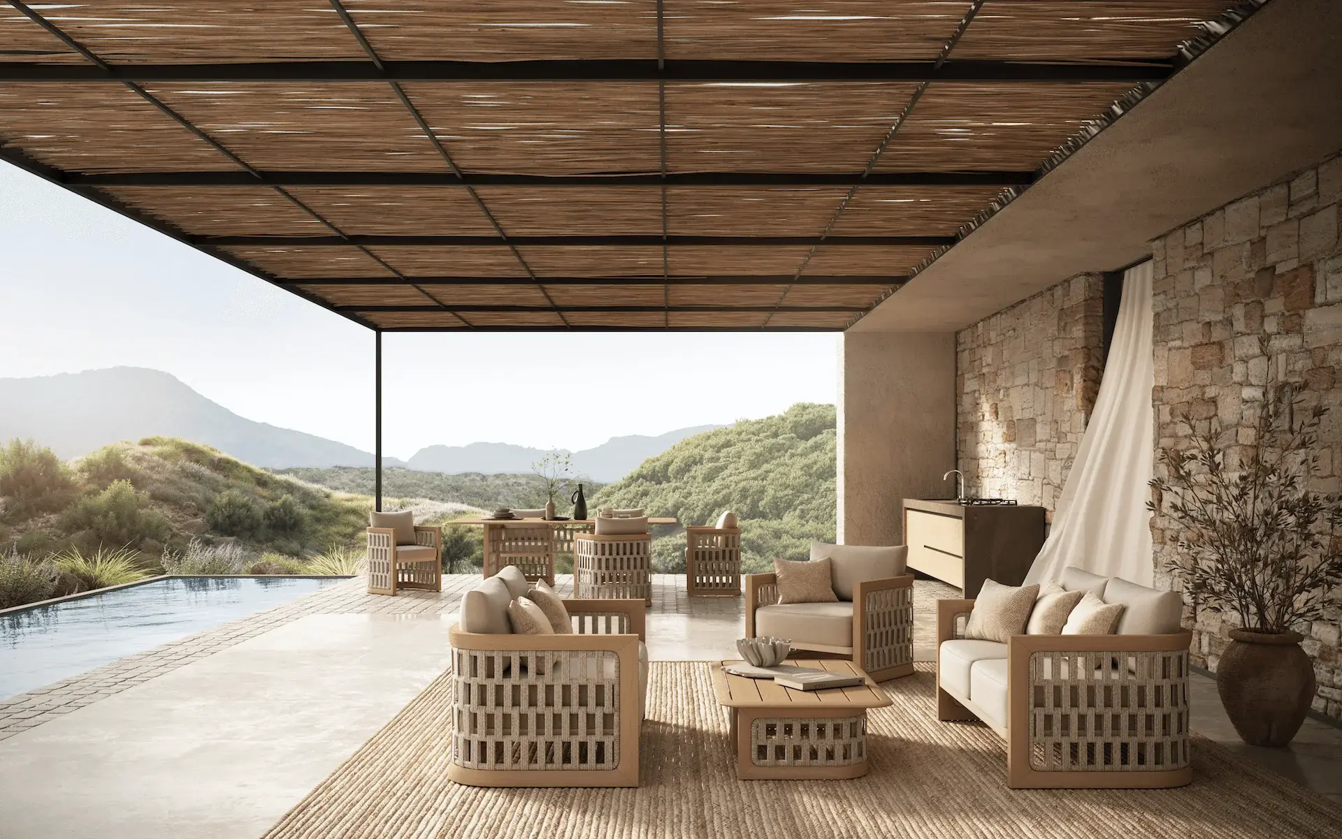 Luxury outdoor lounge with woven armchairs, stone wall, and panoramic mountain views under a shaded pergola.