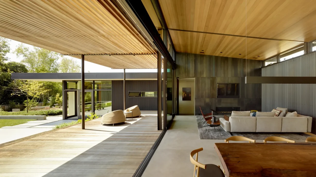 Contemporary open-plan home with wood ceilings, sliding glass walls, and seamless indoor-outdoor connection.