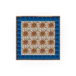 Top-down view of the Vedrà table, revealing the intricate relief ceramic tiles and the central sun pattern inspired by Ibiza sunsets.