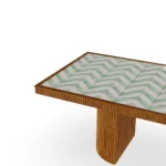 Close-up looking down at the Benirrás table, focusing on the artisanal ceramic inlay and the fine grain of the iroko wood frame.