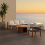 Mediterrazza low-profile wooden lounge chair set under a stone archway with a Mediterranean sea view.