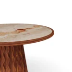 Close-up of Fuengirola table showing the wavy relief iroko base and the natural red veining of the Aegean Rose marble top.