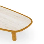 Detailed view of the tabletop corner, where the smooth iroko wood border meets the textured, organically shaped travertine inlay.