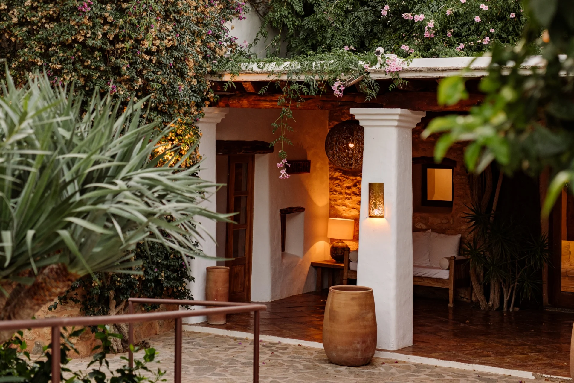 Traditional Ibiza agroturismo villa entrance with whitewashed walls, terracotta pots, and Mediterranean greenery.