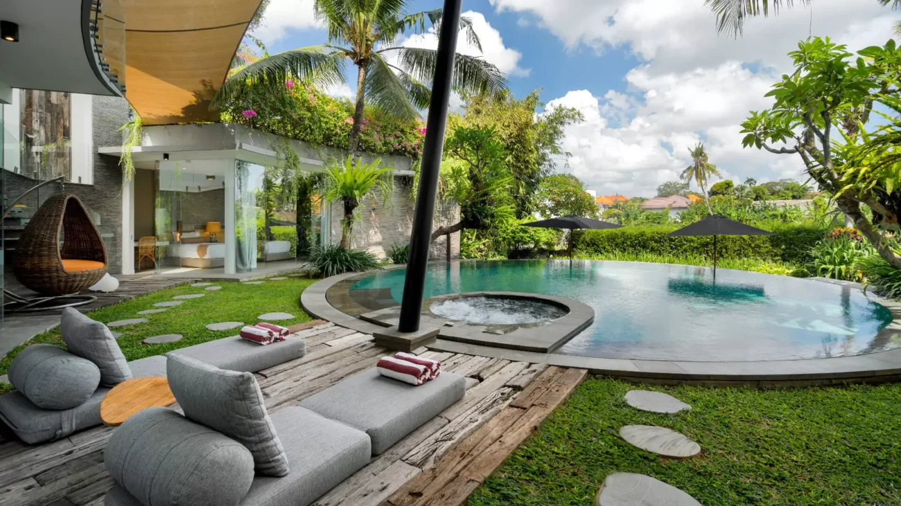 Tropical villa with infinity pool, jacuzzi, and lush garden surrounded by palm trees and modern outdoor lounge.