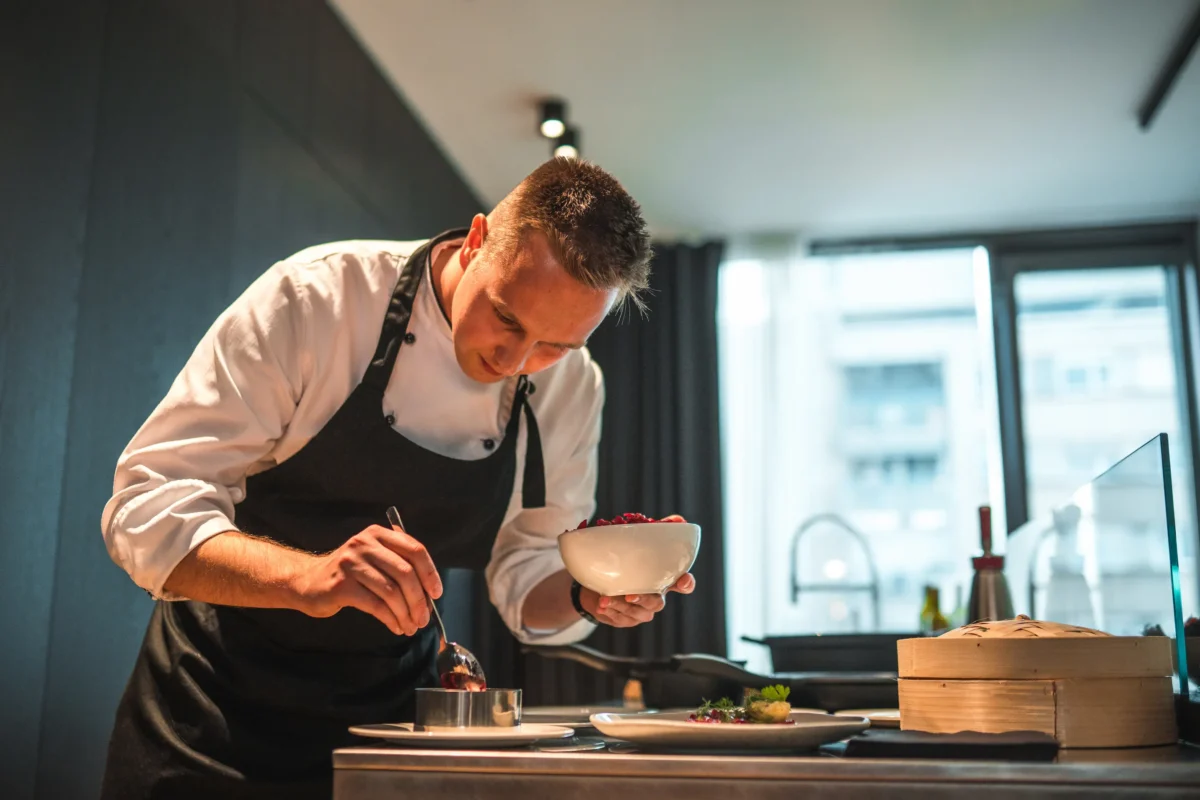Private chef carefully plating a fine dining dish in a luxury residence kitchen.