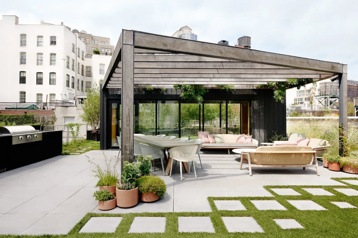 Contemporary New York rooftop terrace with pergola, outdoor lounge seating, and landscaped planters creating a calm urban retreat above the city.