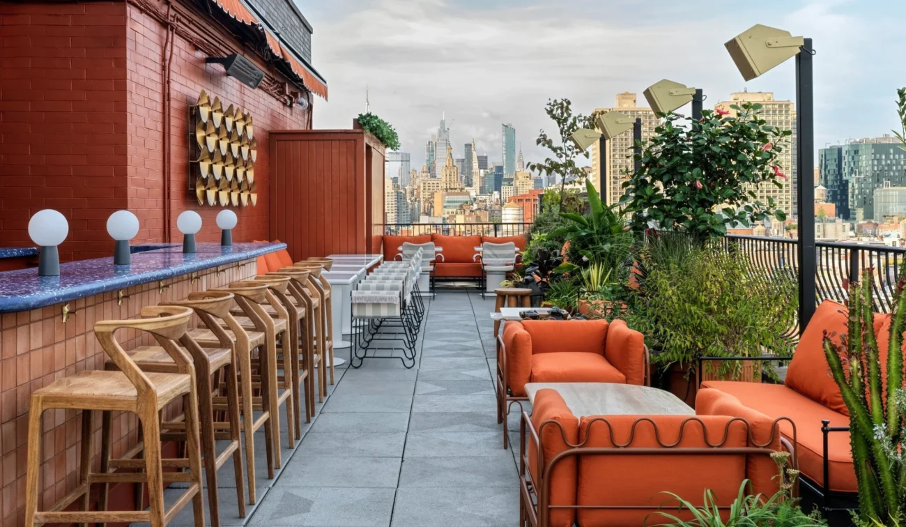 Stylish Manhattan rooftop bar and lounge with warm-toned seating, curated greenery, and skyline views embodying refined urban outdoor living.