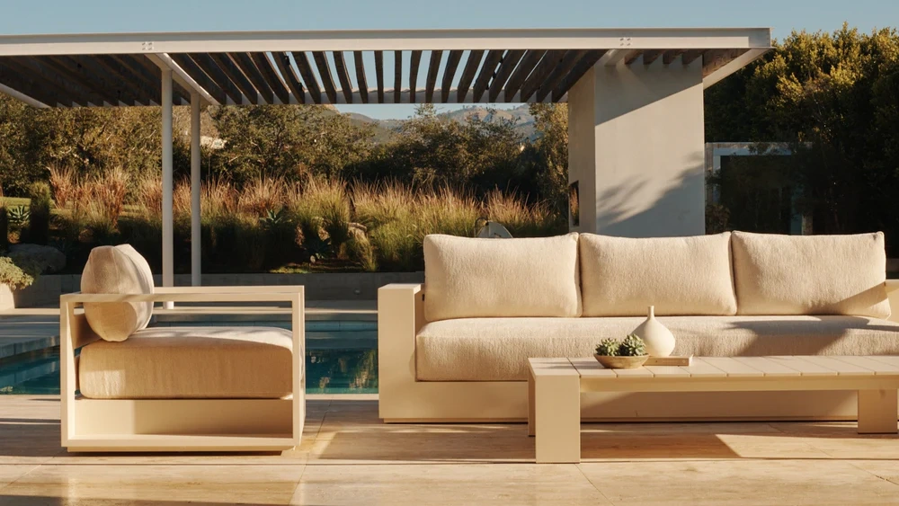 Modern outdoor seating arrangement beside a pool, featuring soft neutral tones and architecture-led design for relaxed social living.