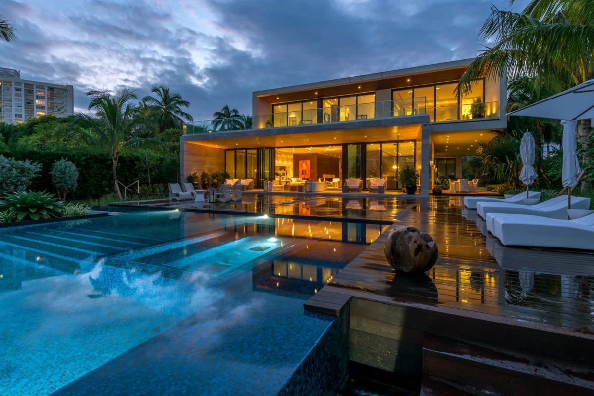 Mediterranean-style luxury villa in Miami featuring palm-lined courtyard, swimming pool, and evening outdoor ambiance