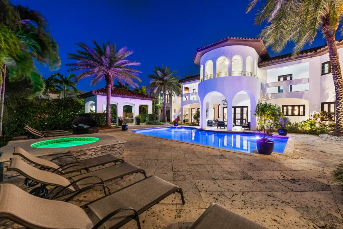 Modern Miami high-end villa with illuminated pool, expansive terrace, and seamless indoor-outdoor living at dusk