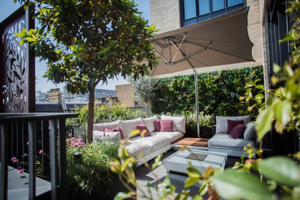 Luxury London roof terrace with modular outdoor seating, parasol shade, and lush planting creating an elegant urban outdoor living space.