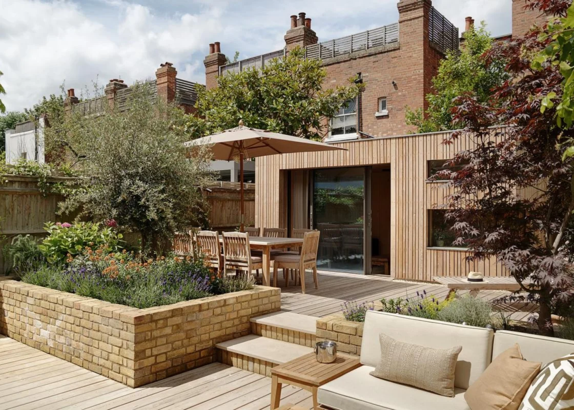Contemporary London townhouse garden with timber terrace, built-in planters, and outdoor dining area designed for year-round outdoor living.