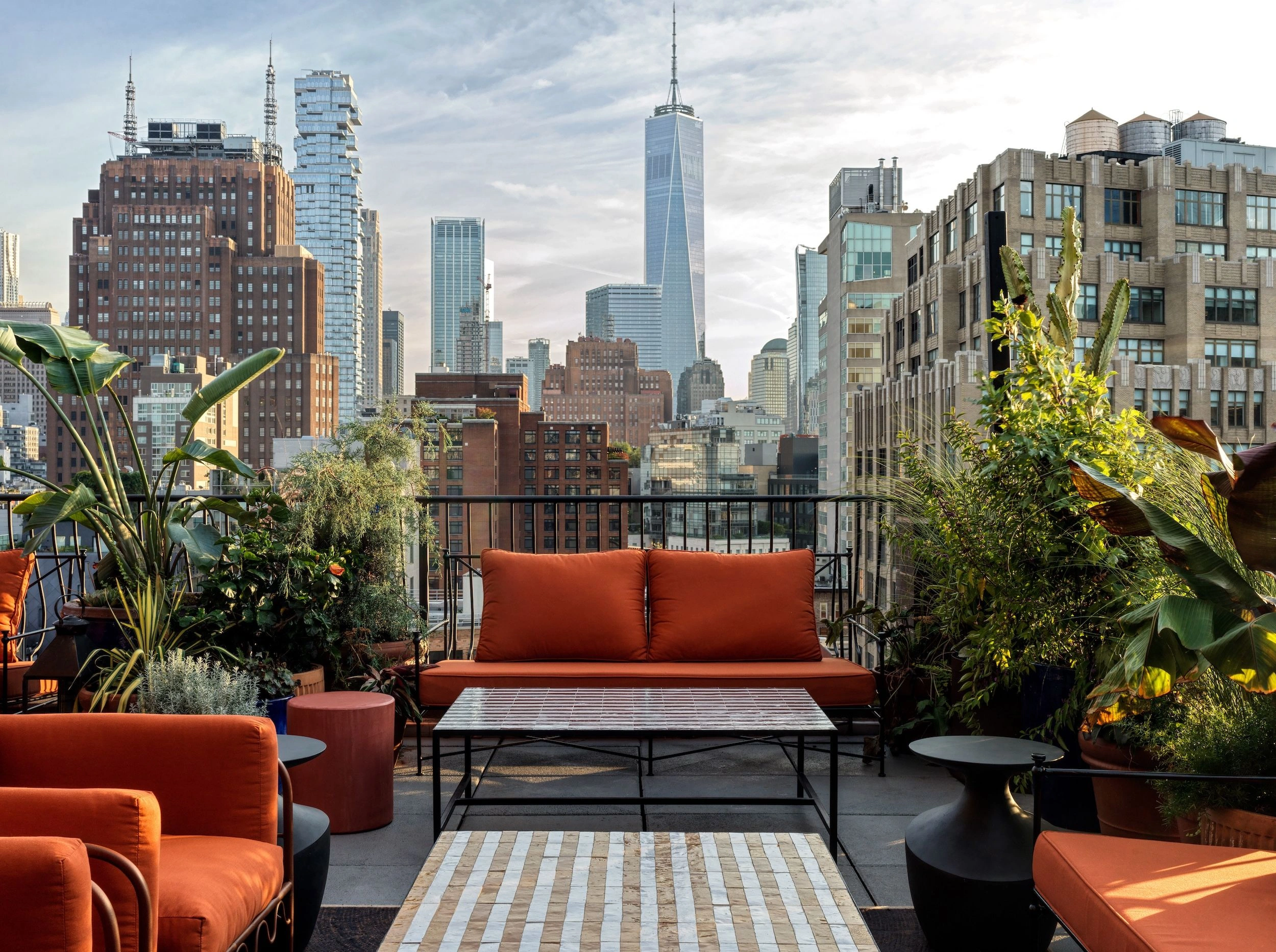 Luxury New York rooftop seating area overlooking the skyline, featuring modern outdoor furniture and lush planting for elevated city living.