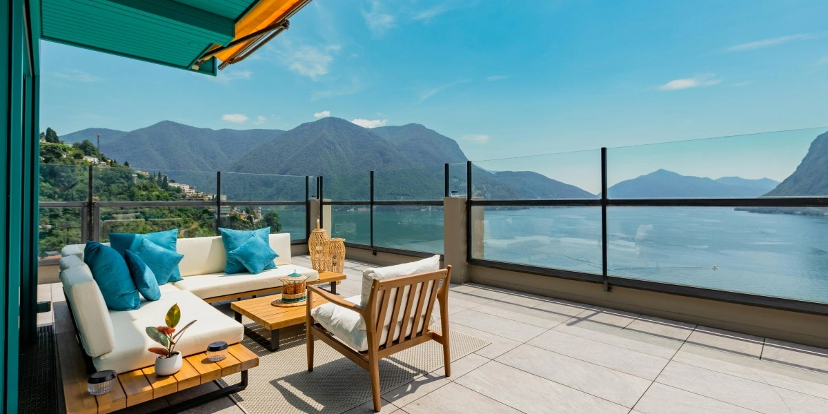 Luxury outdoor seating with woven sofas and neutral cushions in a serene indoor-outdoor living space surrounded by greenery.