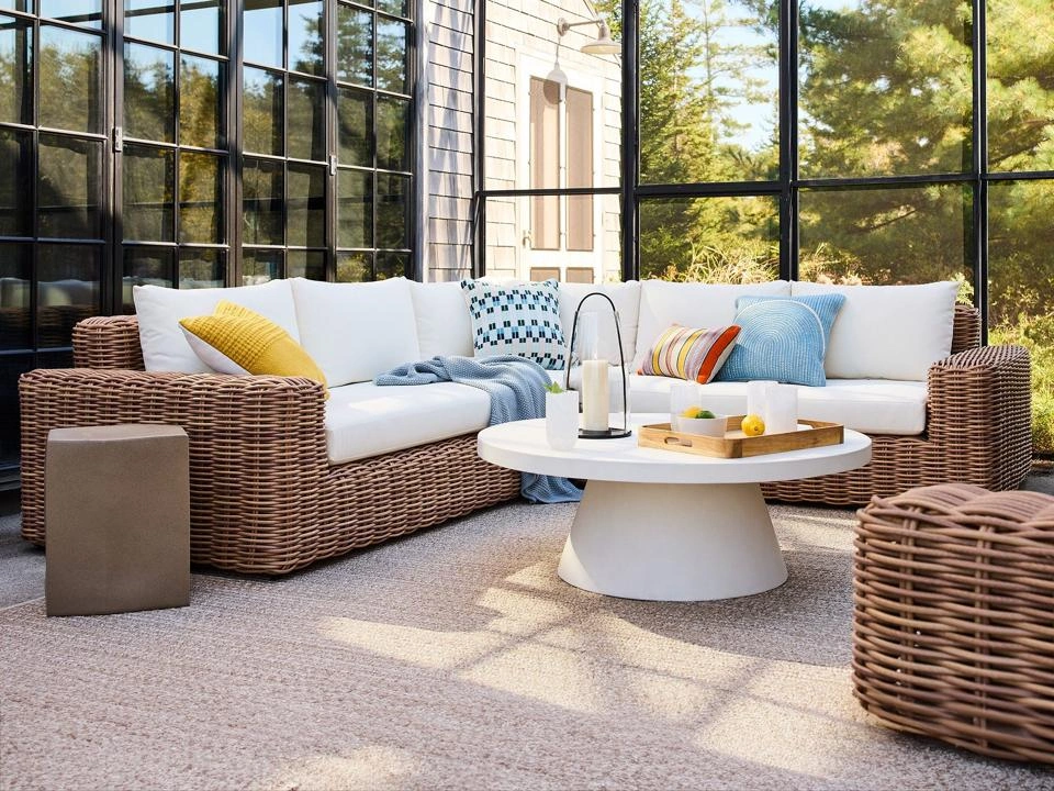 Luxury outdoor seating with woven sofas and neutral cushions in a serene indoor-outdoor living space