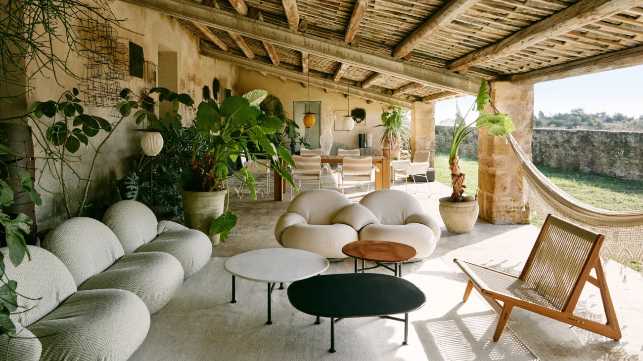 Mediterranean-inspired outdoor lounge with organic outdoor seating, textured upholstery, and natural materials, set under a rustic covered structure that enhances comfort across all seasons.