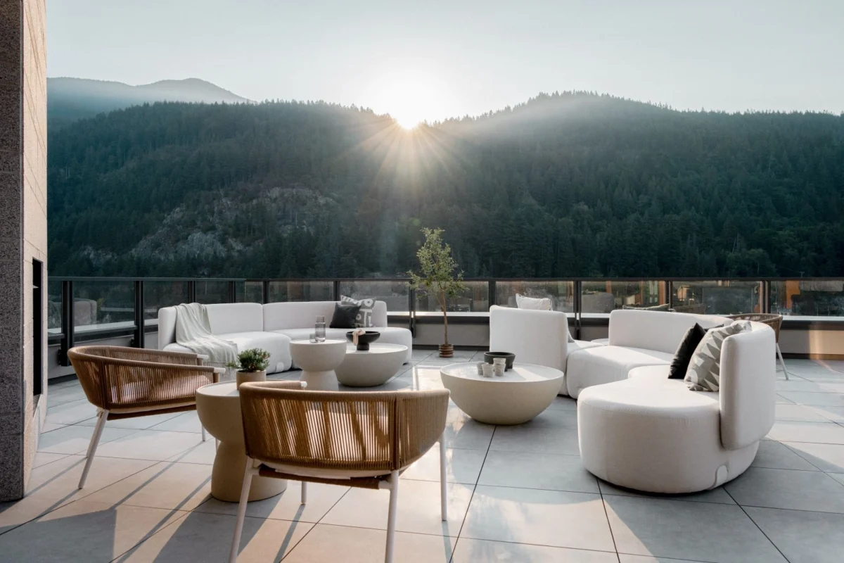 Luxury outdoor lounge on a panoramic terrace featuring curved outdoor seating and sculptural tables, framed by mountain views and soft natural light for an elegant year-round outdoor living experience.