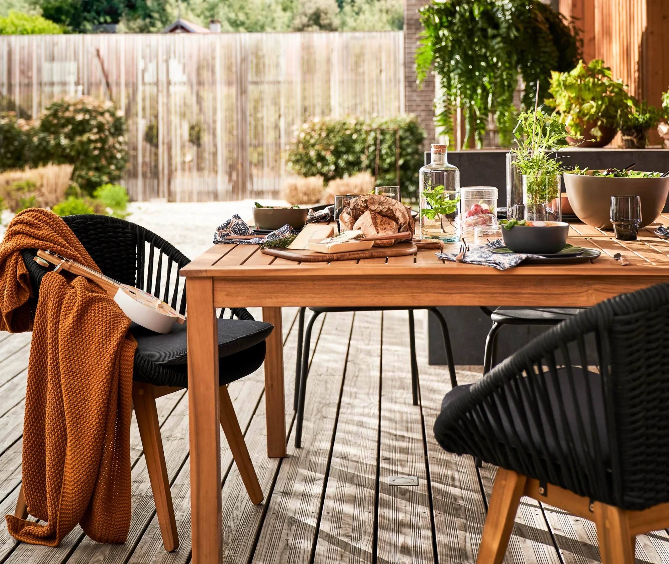 Timeless patio dining setup featuring a solid wood outdoor dining table and woven dining chairs, styled with natural textures for relaxed yet refined outdoor living.