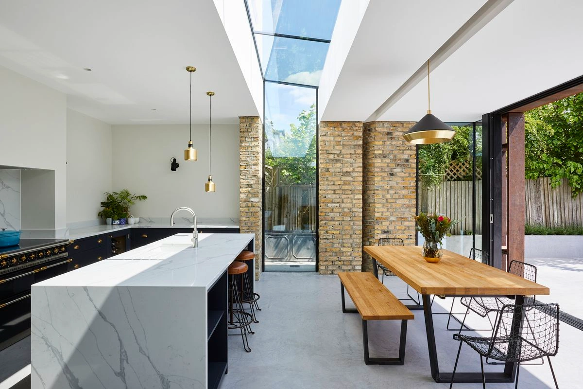 Contemporary Mediterranean kitchen with natural materials and direct access to an outdoor dining area, blending interior design with open-air living.