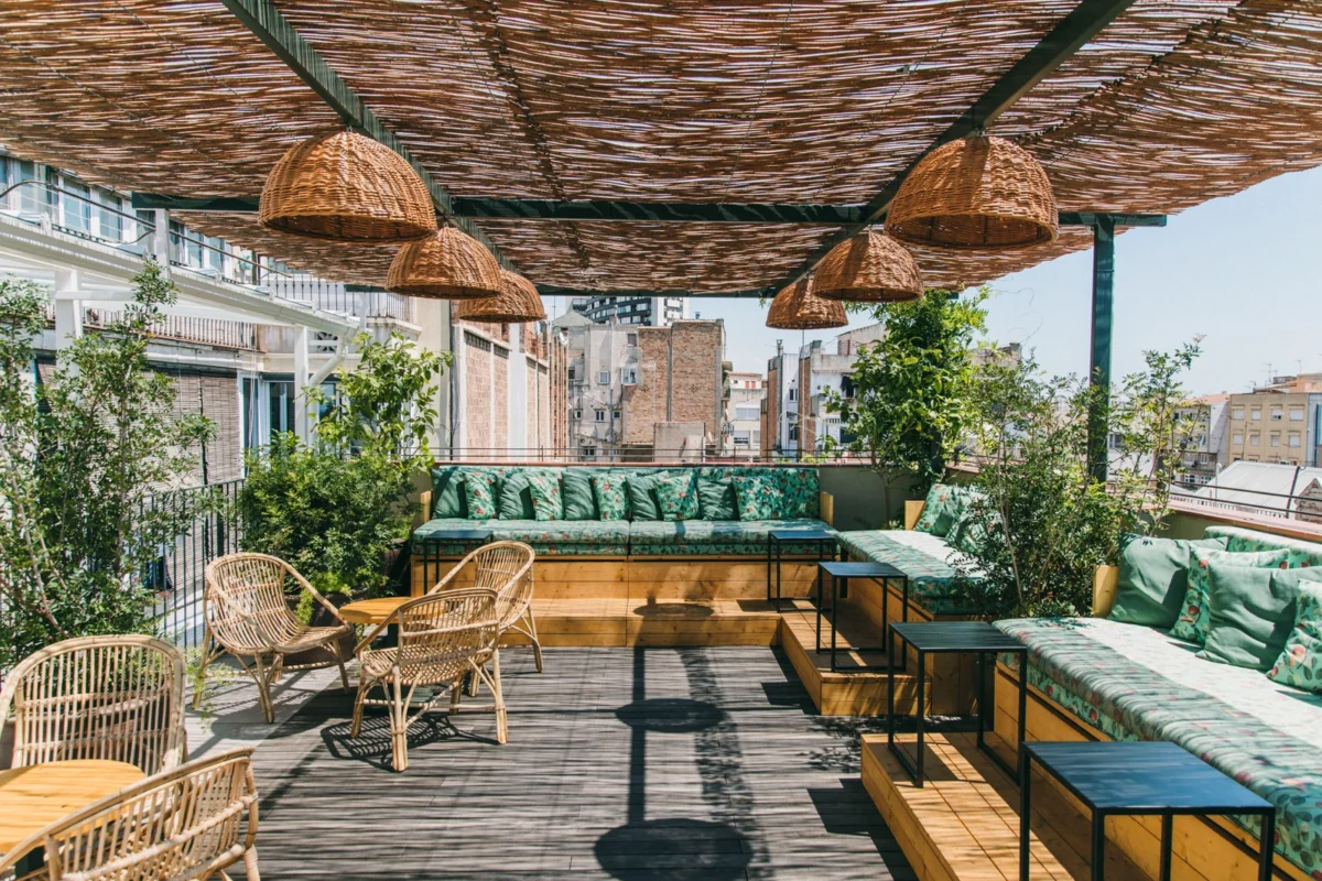 Design-led rooftop terrace in Barcelona with woven lighting, Mediterranean plants, and relaxed open-air seating, showcasing contemporary Barcelona outdoor dining culture.