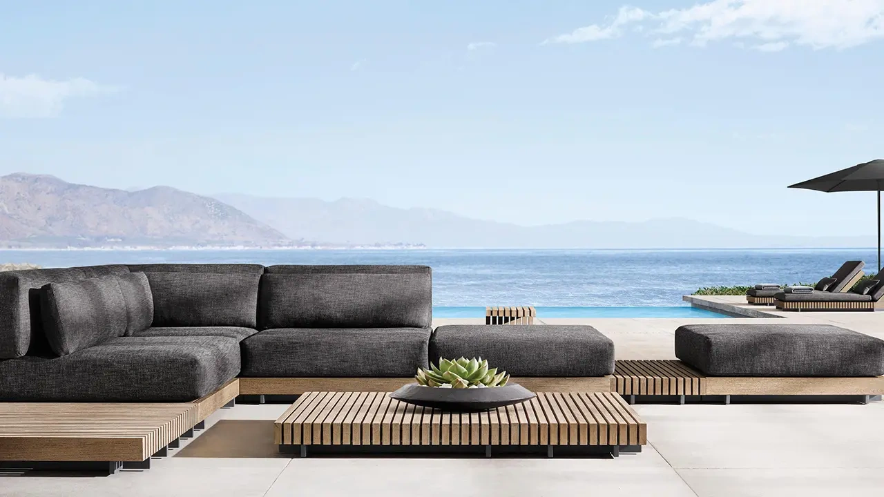 Luxury teak outdoor furniture including lounge seating, dining table, and sectional sofas styled on contemporary oceanfront terraces and poolside decks, showcasing natural wood tones and refined coastal architecture.