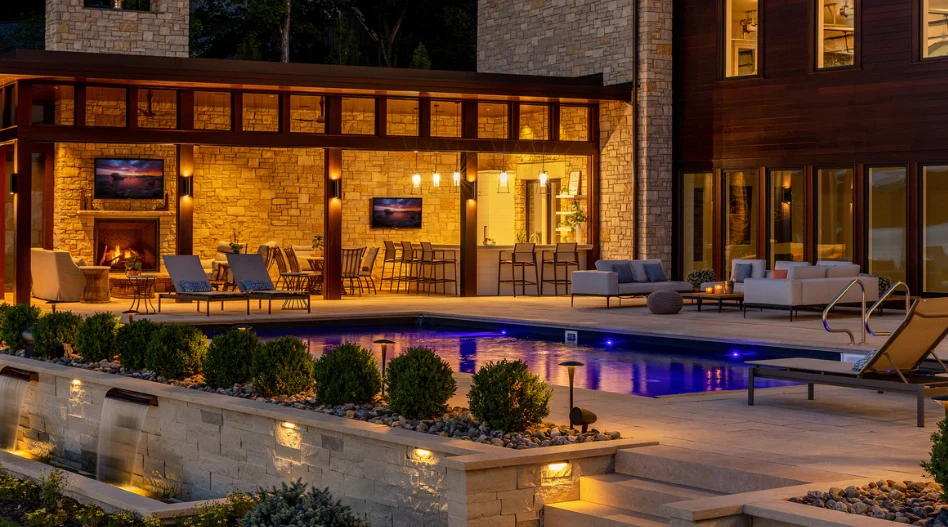 Luxurious outdoor patio at dusk with a glowing pool, elegant seating, fireplace, and ambient lighting. The scene exudes warmth and relaxation, showcasing the comfort of luxury outdoor spaces.