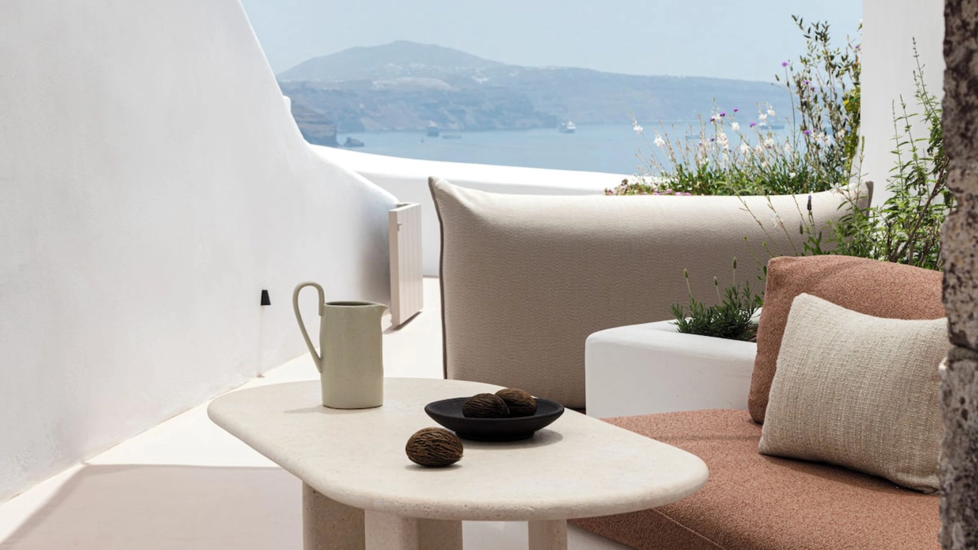 Cycladic architecture with whitewashed terraces and luxury outdoor seating overlooking the Aegean Sea in Mediterranean island homes.