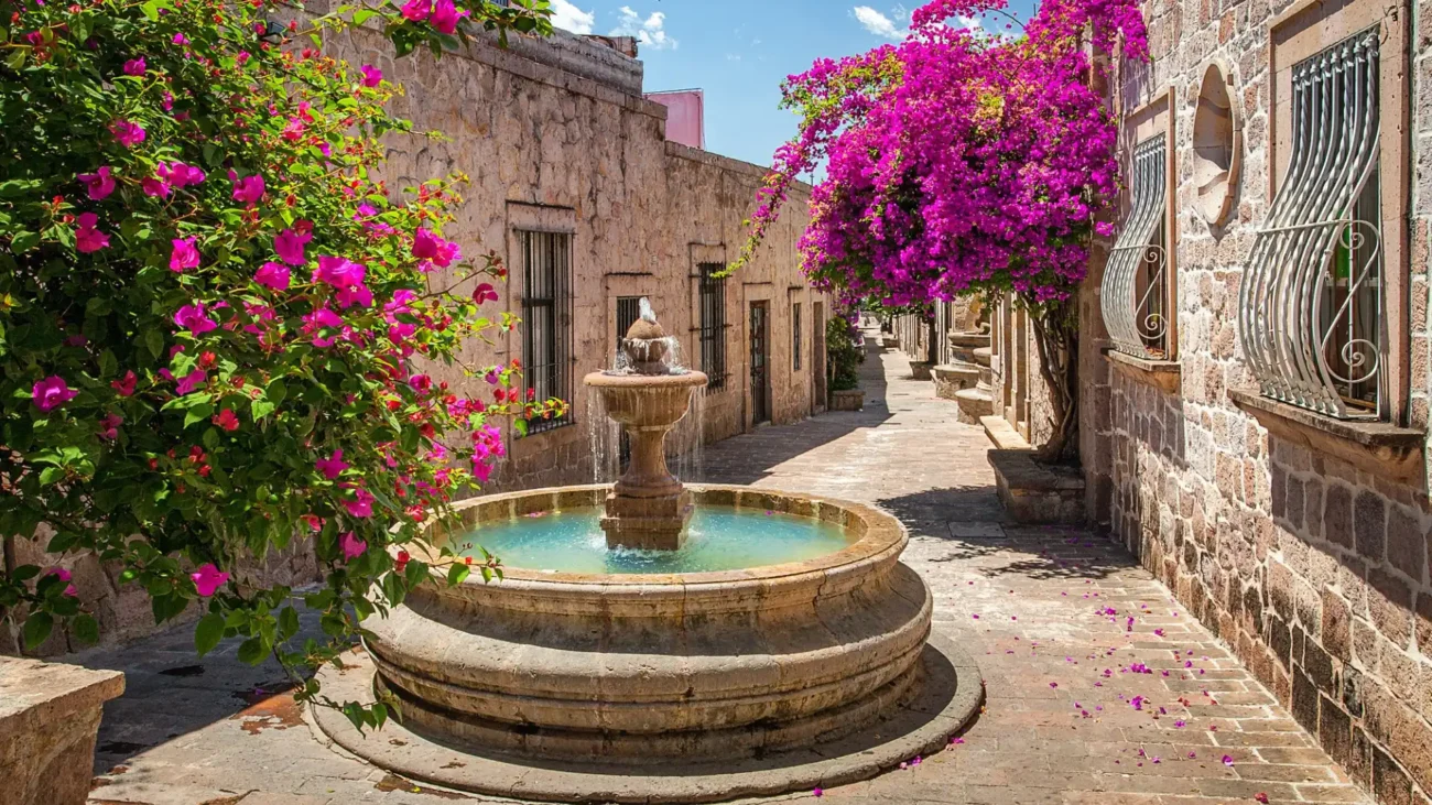 Mediterranean courtyard garden with elegant stone fountain, lush greenery, and traditional architectural details creating a tranquil water feature centerpiece.