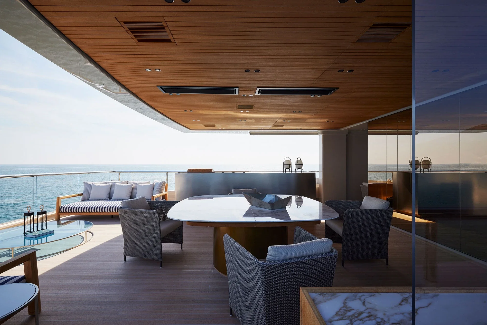 Luxurious yacht deck with wooden ceiling, modern dining set, and plush sofas overlooking the ocean. The scene is serene and elegant.