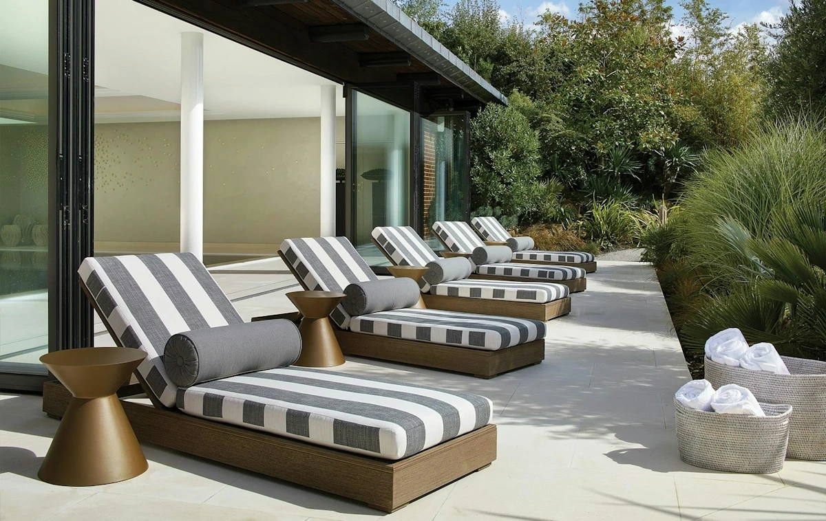Outdoor luxury living design featuring a contemporary villa garden lounge with modular seating, natural greenery, wooden decking, and elegant exterior furniture in a modern architectural setting.