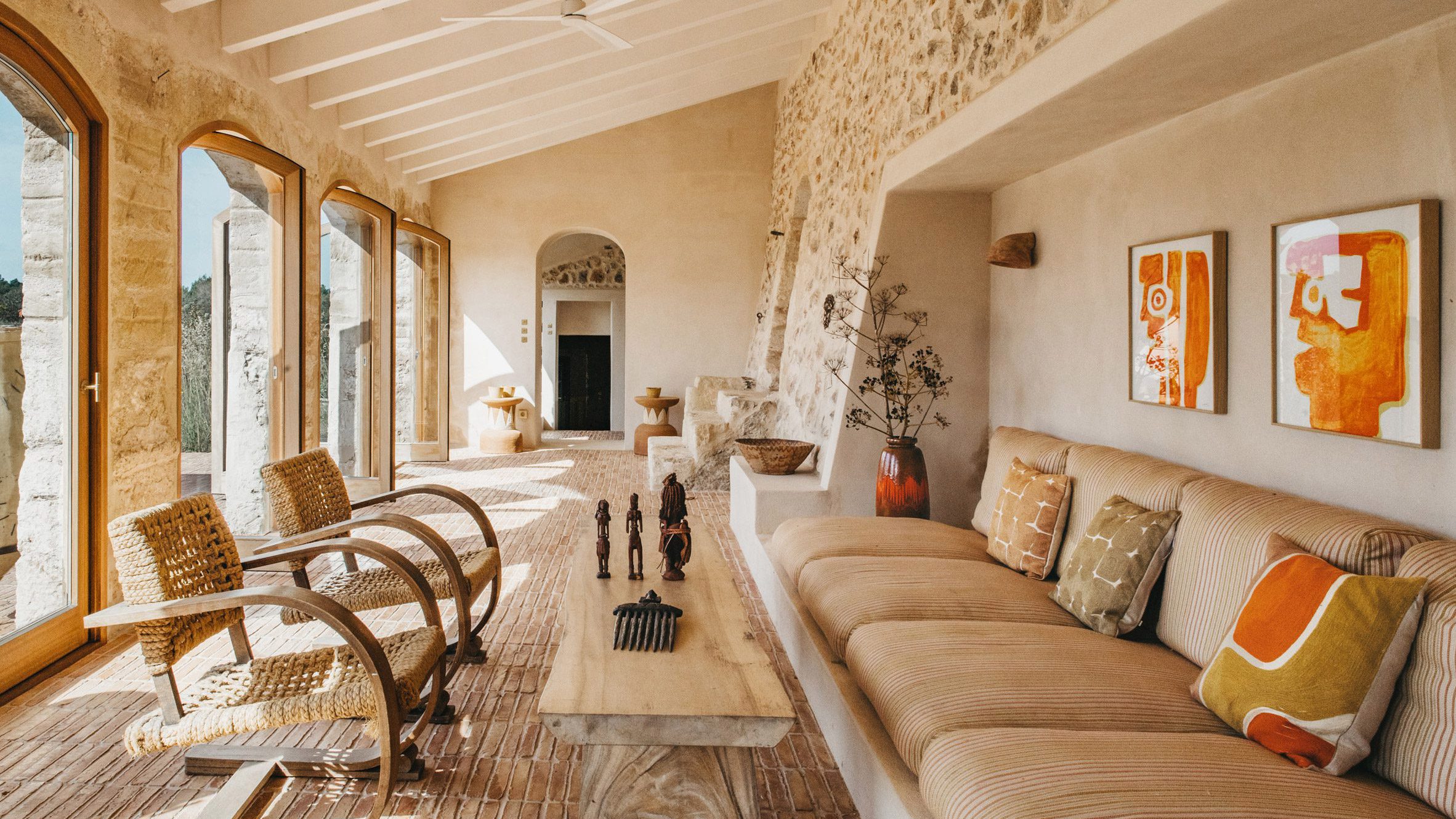 Contemporary Mediterranean villa in Menorca featuring natural stone walls, minimalist architecture and seamless indoor-outdoor living under warm sunlight