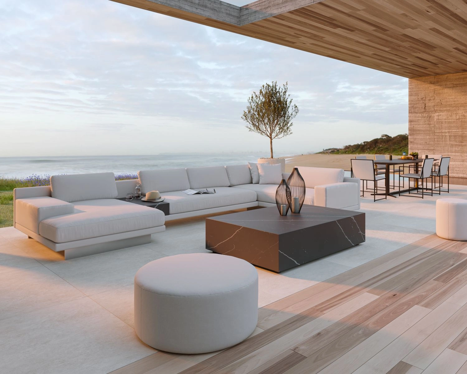 Modern minimalist luxury outdoor patio with white sofas and chairs overlooks the ocean. A sleek coffee table centers the seating area.