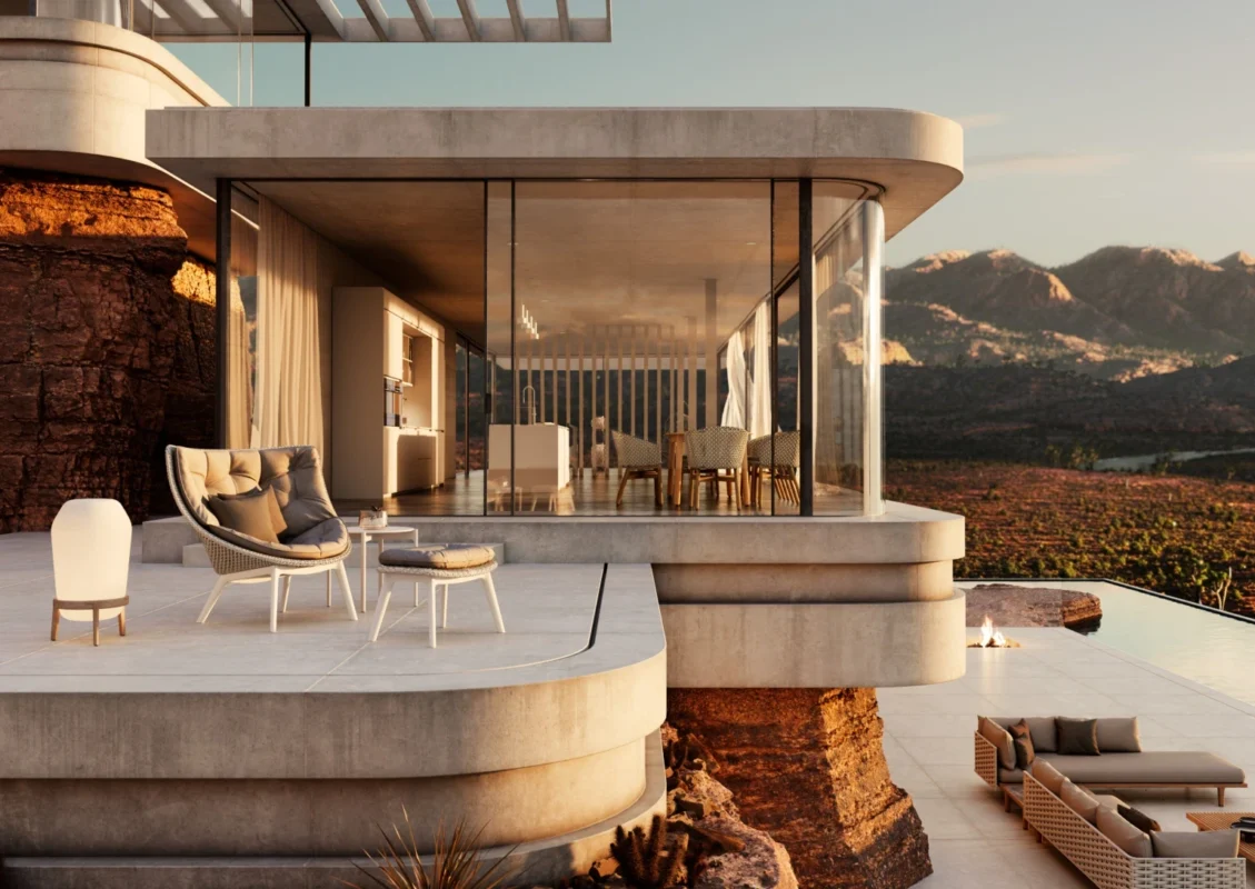 Modern concrete house with large glass walls offers panoramic mountain views at sunset. A patio with stylish furniture designed by Sebastian Herkner and infinity pool adds elegance.