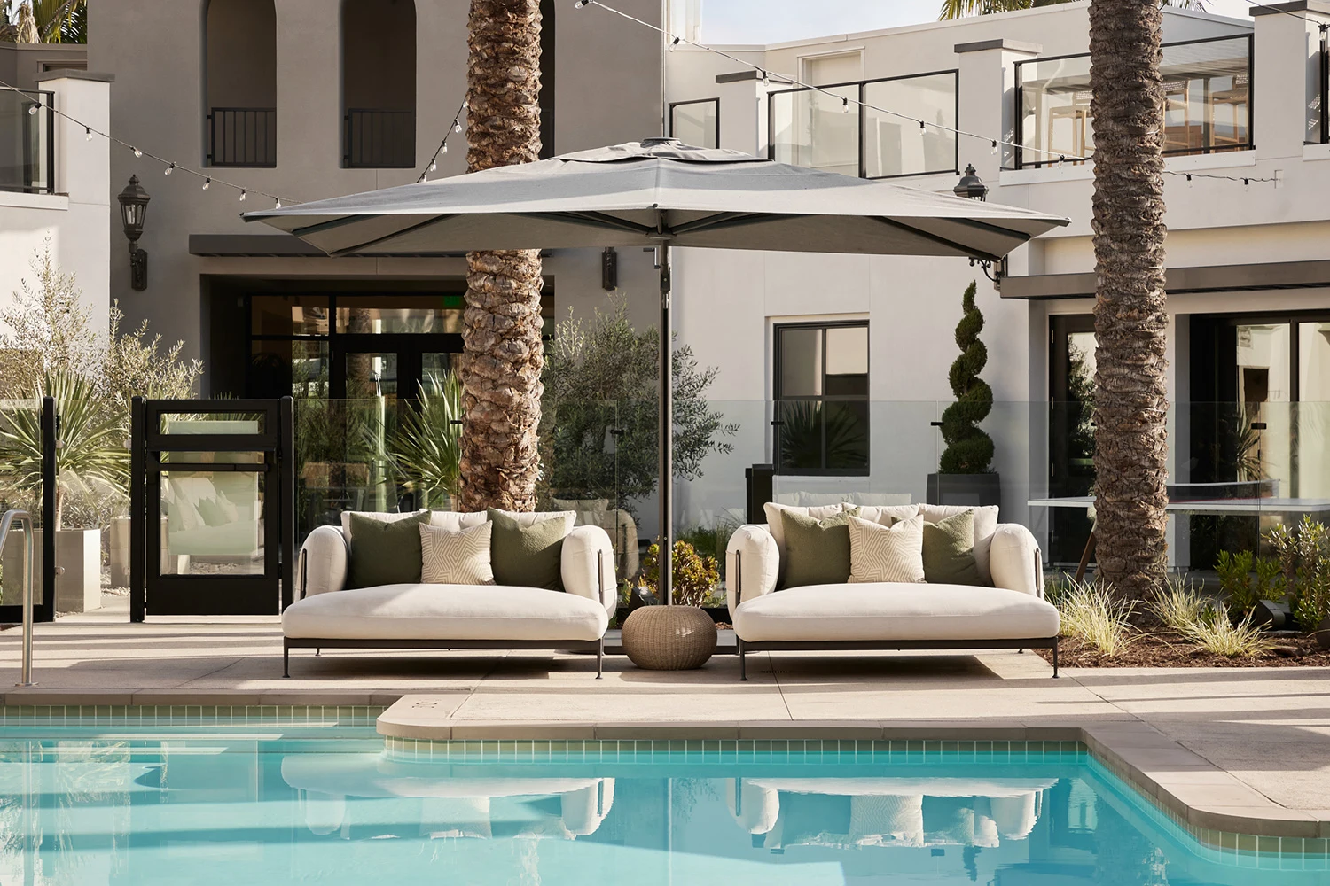 Mediterranean design fairs showcasing luxury outdoor lounge spaces with natural textures, contemporary furniture, and warm architectural lighting.
