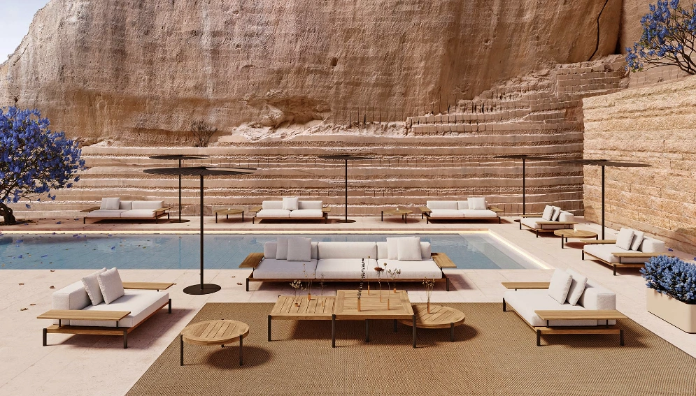 Luxurious outdoor lounge with the Lamadera Collection by Francesco Meda by a pool. Rugged stone wall and two blooming purple trees add serenity.