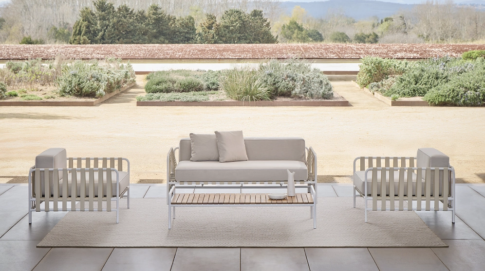 Modern patio furniture set, the Onsen Collection by Francesco Meda, on a spacious terrace with a garden view. Beige tones and sleek design evoke a serene, minimalist ambiance.